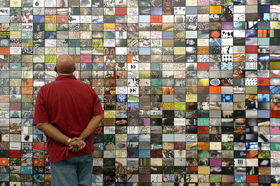 man standing in front of a wall full of small colorful images